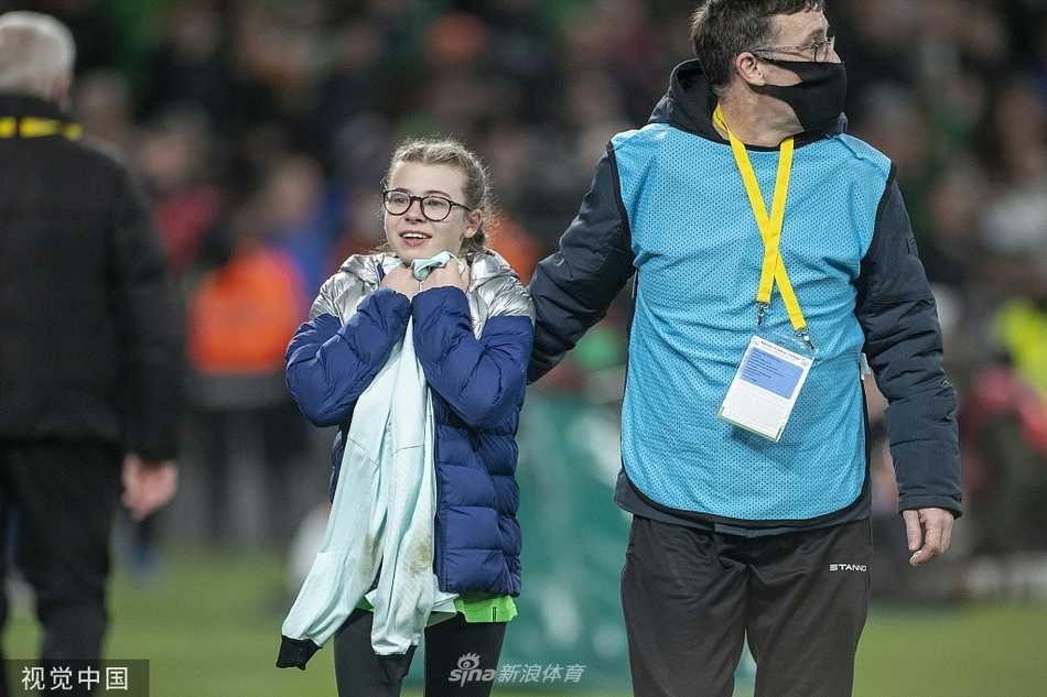 小女孩已经在家人或工作人员的陪伴下，穿上了那件宽大的葡萄牙7号球衣。她低头看着胸前的名字和号码，嘴角露出幸福的笑容，这件球衣对她来说无疑是最珍贵的宝物。