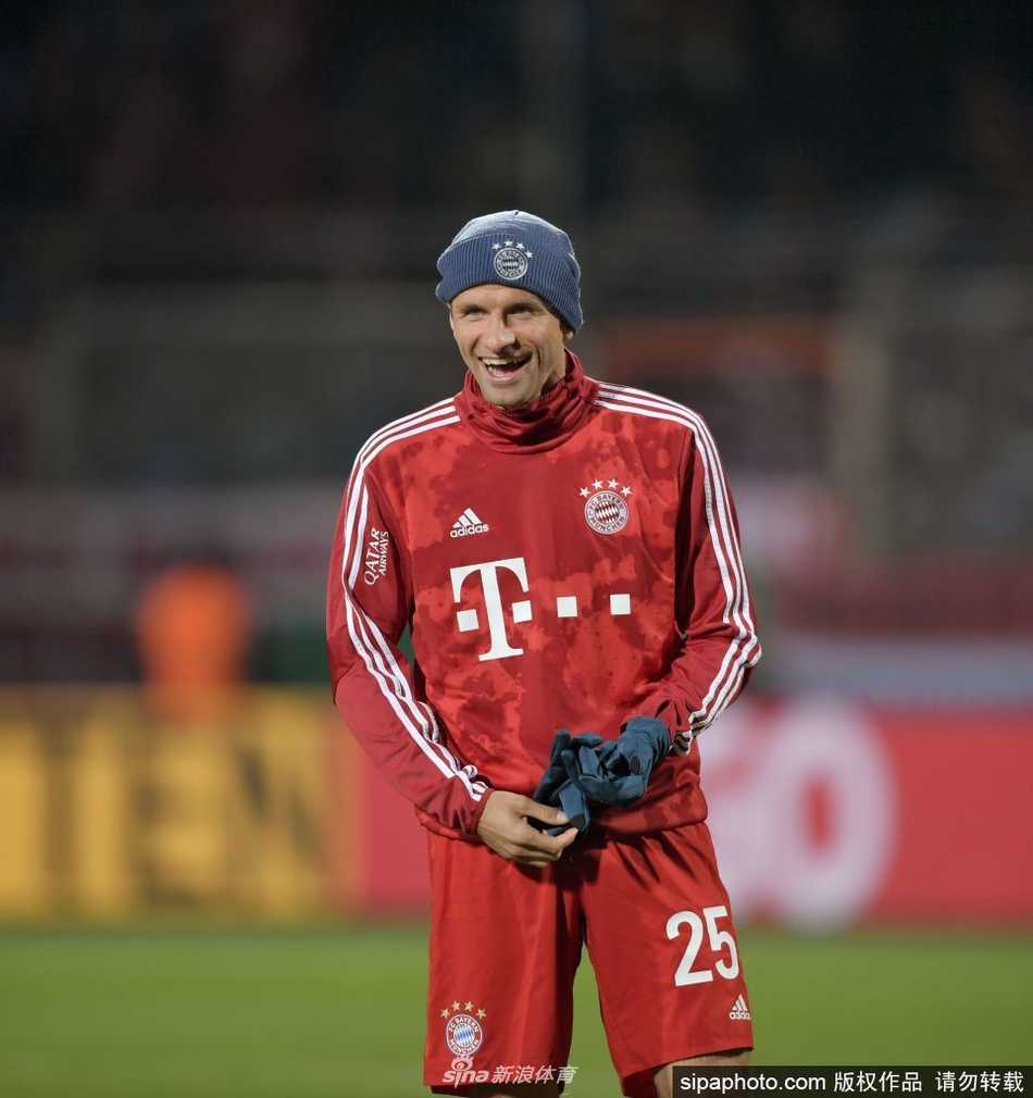 穆勒与儿童俱乐部吉祥物伯尼熊击掌互动，两人表情夸张搞怪，生动展现了穆勒与孩子们打成一片的独特亲和力。