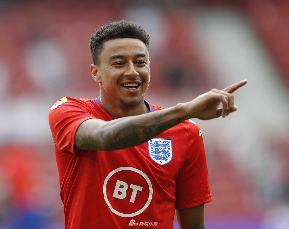 林加德身穿白色T恤，双手竖起大拇指，脸上洋溢着标志性的灿烂笑容。即使在家观看比赛，他的心情也似乎不错，这份乐观也感染着每一个支持英格兰的球迷。