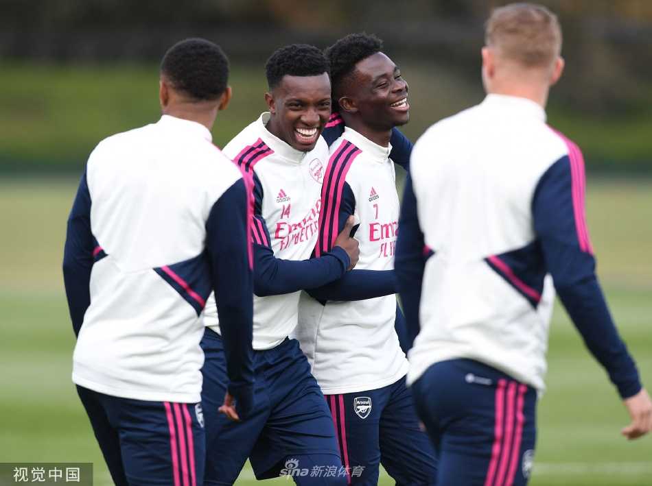 主教练阿尔特塔手持战术板，神情严肃地向队员讲解对阵曼城的核心战术部署，队员们围拢倾听，目光专注。