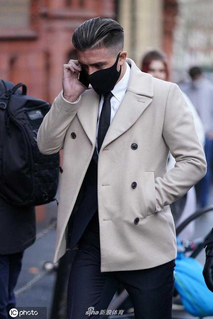 在走向法庭的台阶上，格拉利什的侧脸轮廓分明，剪裁得体的黑色西装与奶油色大衣搭配尽显绅士风度，但这身行头与他一早面临的交通肇事指控形成了鲜明而讽刺的对比