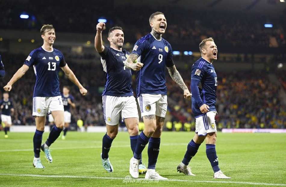 苏格兰队长约翰·麦金在进球瞬间背身倚住防守球员，正灵巧转身准备起脚劲射，表情专注而决绝。