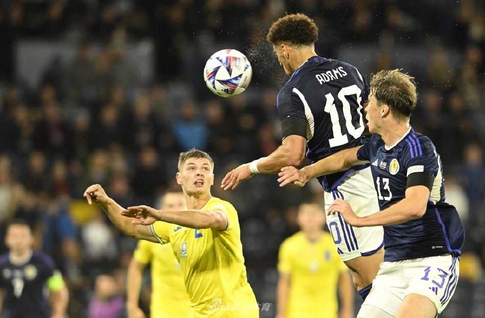 乌克兰队球员在比赛后神情落寞，背景是正在欢庆胜利的苏格兰队员，画面形成了鲜明的情感对比。