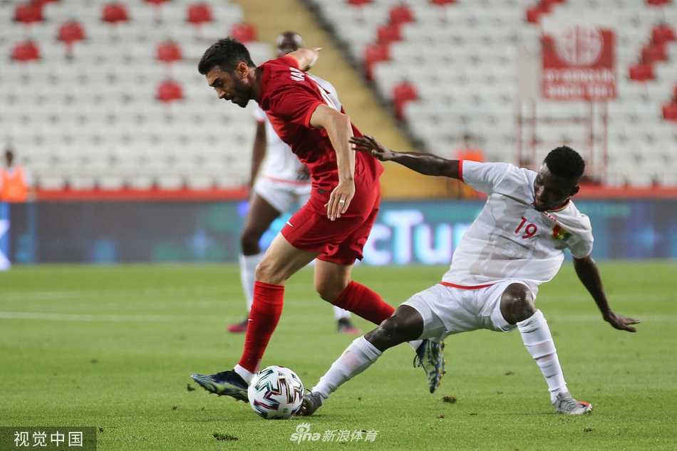 土耳其队前锋在几内亚防守球员的贴身紧逼下，正以不屈的姿态奋力争夺球权，空气中弥漫着友谊赛也毫不退让的火药味