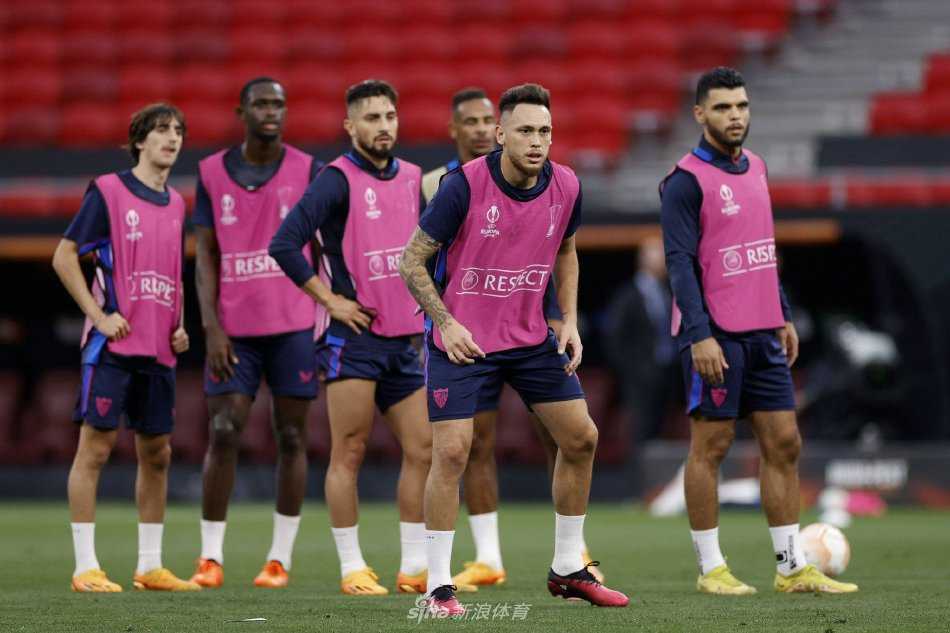 布达佩斯训练场上，塞维利亚球员围成紧密的圆圈进行战术部署，神情专注，决战氛围浓厚。