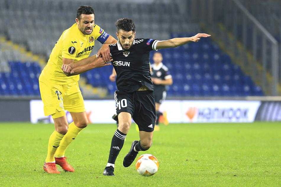 比利亚雷亚尔球员破门瞬间，激情挥拳庆祝，身后的卡拉巴赫防守球员面露无奈之色