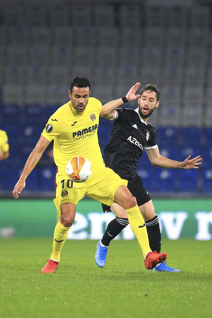 完成梅开二度的比利亚雷亚尔前锋帕科阿尔卡塞尔被队友簇拥，脸上洋溢着胜利的喜悦，背景是空旷的体育场看台