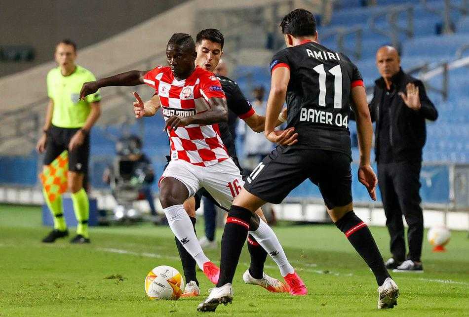 勒沃库森球员列昂·贝利在客场打入关键进球后激情滑跪，以色列沙漠的夜幕下，他的身影如同划破黑暗的闪电，草屑随着他的动作飞扬，定格了药厂反超比分的狂喜瞬间。