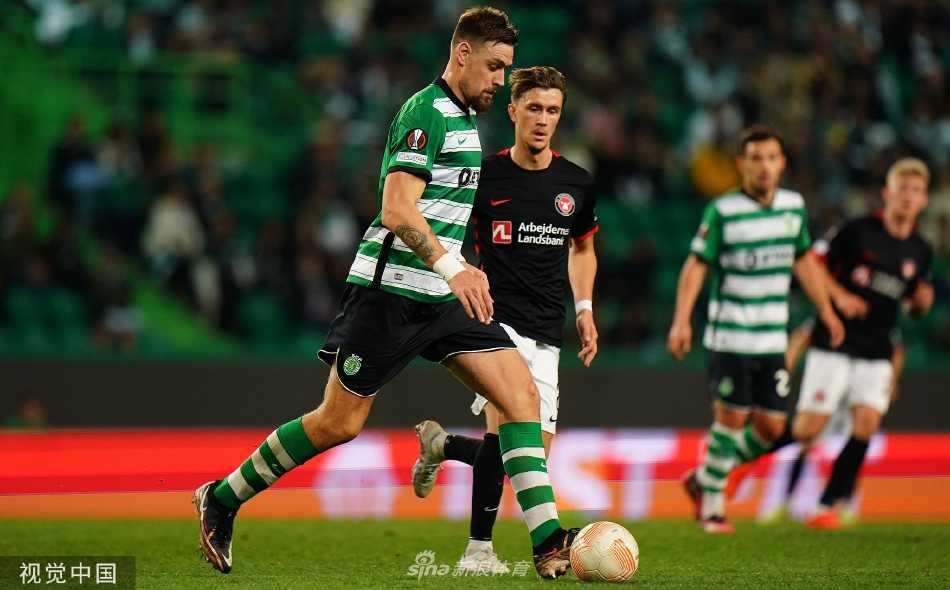 葡萄牙体育队球员带球突破，两名中日德兰队防守球员如影随形进行包夹，三人身影在球场灯光的照射下交错，展现出比赛的高强度对抗。