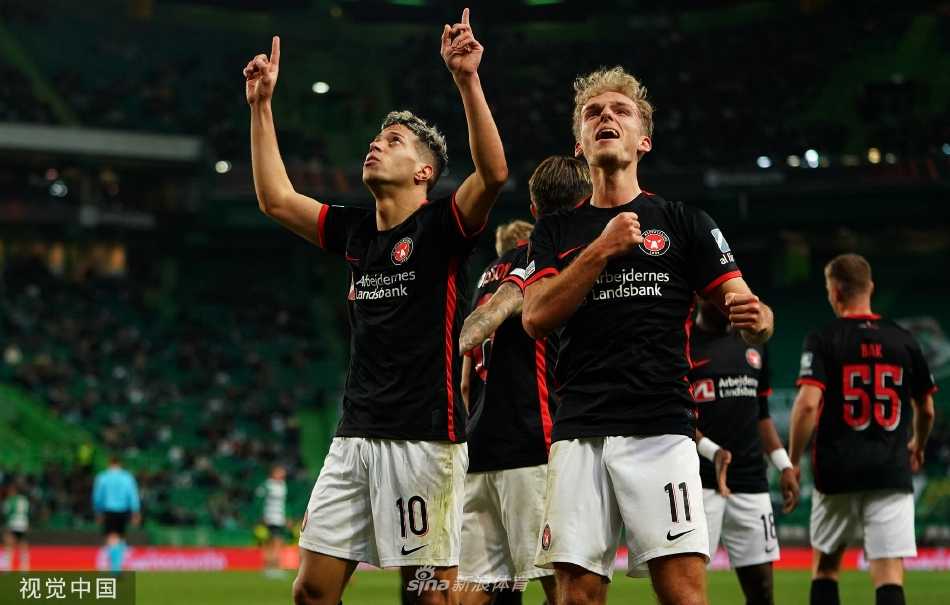 葡萄牙体育队球员张开双臂奔向角旗区疯狂庆祝进球，身后是激动不已奋力追赶的队友，而远处背景里中日德兰队门将则颓然弯腰，形成胜利与失落的鲜明对比。