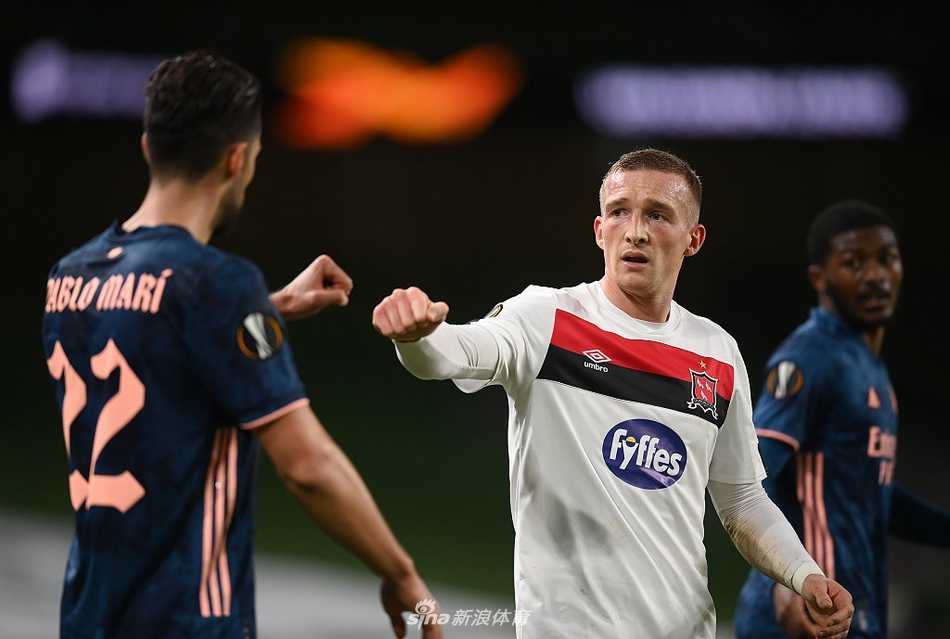 进球后的巴洛贡与队友威洛克击掌相庆，两人脸上洋溢着青春的笑容，背景是爱尔兰都柏林的夜空。