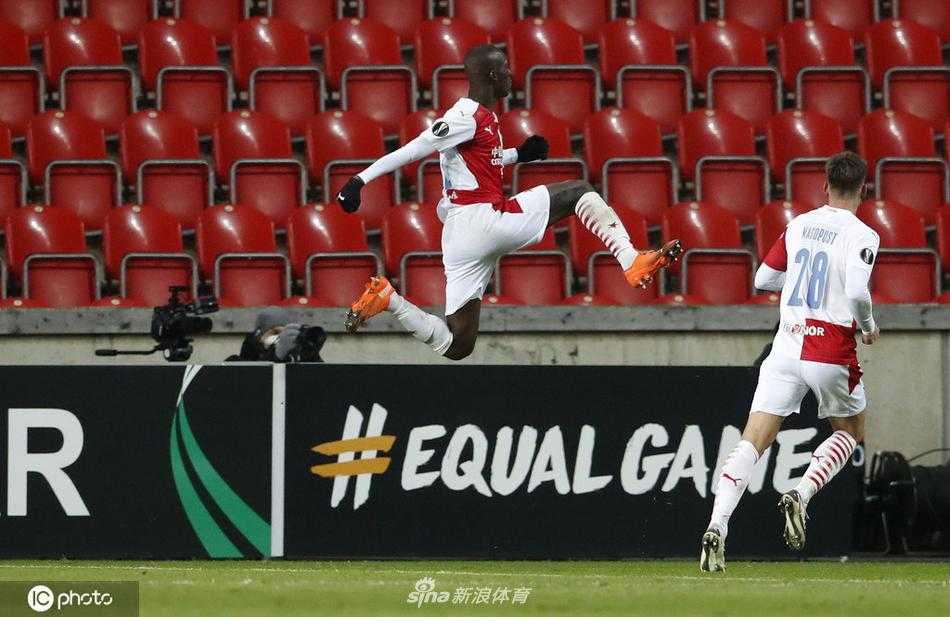 贝尔谢巴工人球员面露无奈，叉腰低头，背景是疯狂庆祝的布拉格斯拉维亚球员，形成鲜明对比