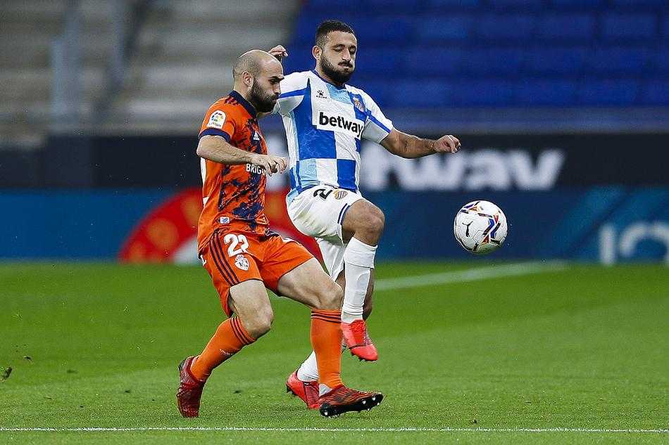 武磊身披纪念夹克，目光凝重地注视着场内激烈拼抢，虽无法登场，心却始终与球队同在。