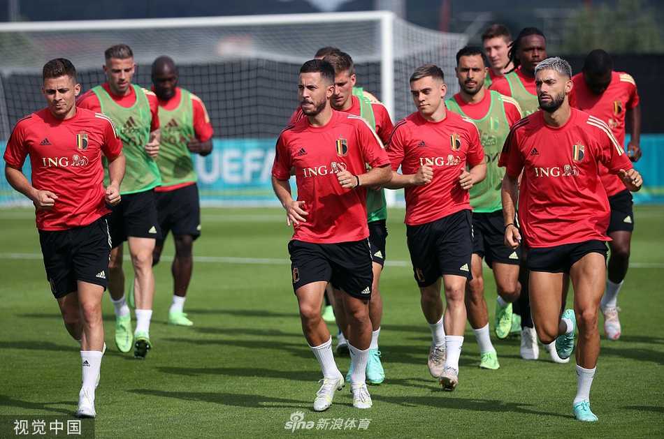 在圣彼得堡的阳光草坪上，一位身着亮黄色背心的比利时队员正全神贯注地控球，而在不远处，他的队友维特塞尔与默尼耶似乎捕捉到了场边某个有趣的瞬间，两人相视一笑，那心照不宣的温暖笑意，仿佛瞬间驱散了大赛前的所有紧张。