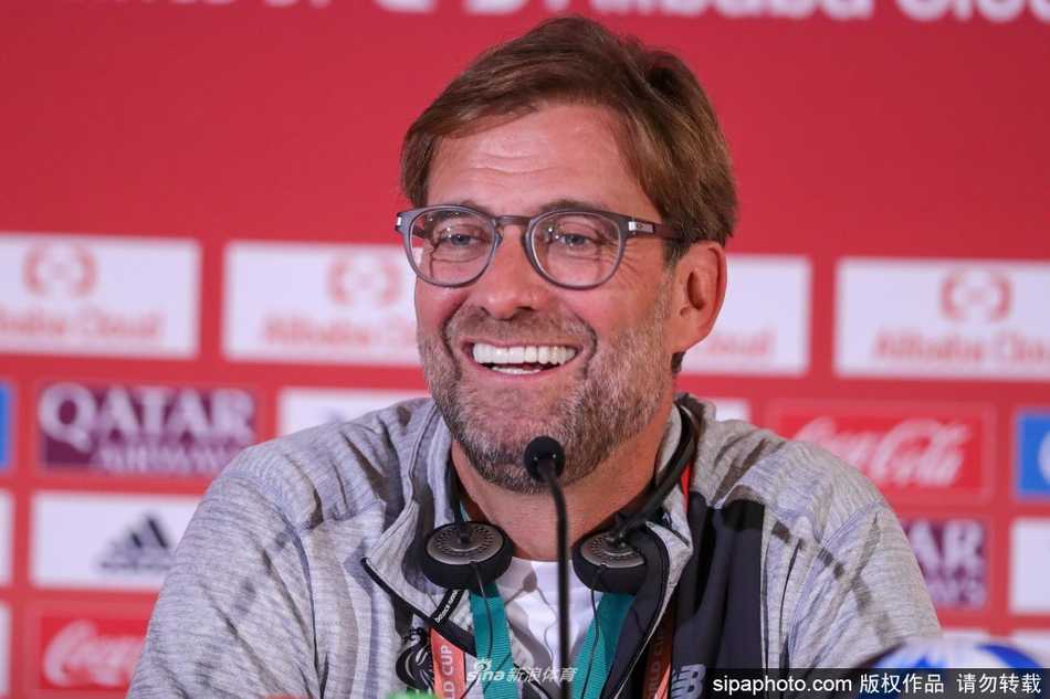 利物浦队长亨德森在漫天金雨中，高高举起英超冠军奖杯，身后是队友们张开双臂欢呼的剪影，整个画面被喜悦的红色灯光和金色纸屑笼罩。