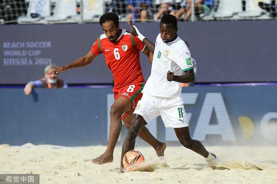 阿曼队球员在莫斯科的夕阳下，于卢日尼基体育场的沙滩上激情滑跪，庆祝球队在对阵塞内加尔的关键战役中取得领先，飞扬的沙粒映衬着他的喜悦。