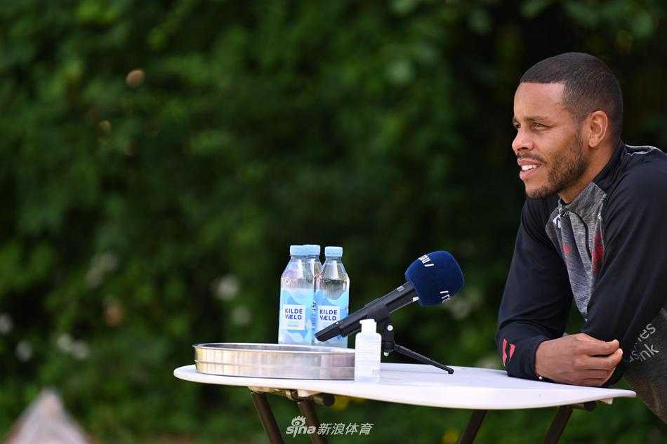 丹麦中场大将托马斯·德莱尼在发布会上目光坚定，嘴角带着一丝微笑，他微微前倾的身体透露出对即将到来的比赛的渴望，胸前的丹麦队徽在闪光灯下格外醒目。