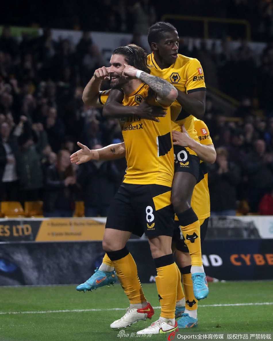 狼队前锋劳尔·希门尼斯在破门后张开双臂，面向看台激情庆祝，身后是沮丧的沃特福德后卫。