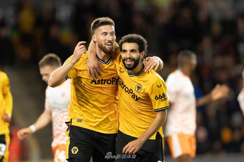 莫利纽球场灯火通明，狼队球员庆祝进球，看台上球迷欢呼雀跃形成一片金色海洋