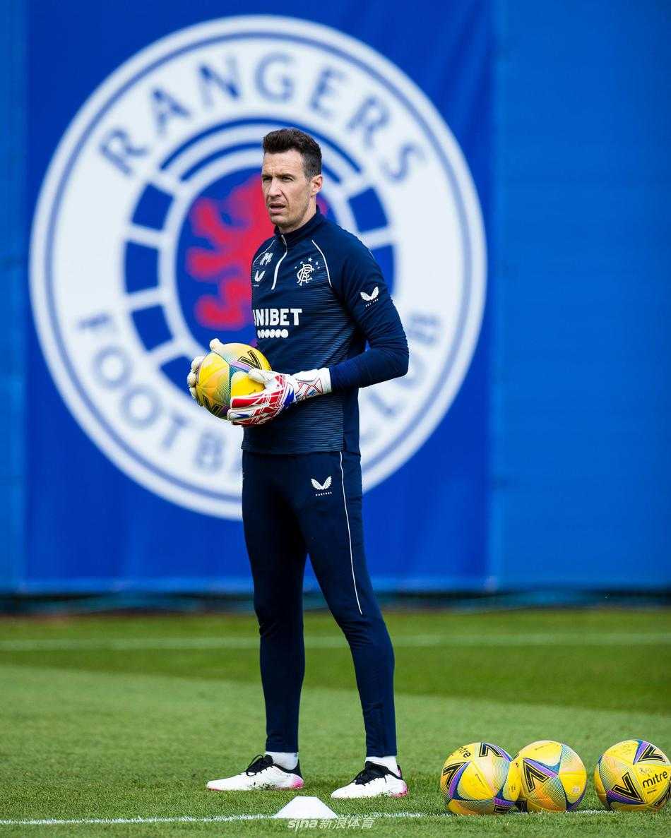 夕阳的余晖洒在训练场上，主教练史蒂文·杰拉德双手抱胸，目光深邃地凝视着远方。他的身影在草地上投下长长的剪影，仿佛一个冷静的指挥家，正在为他的交响乐团敲定最后的高潮乐章。