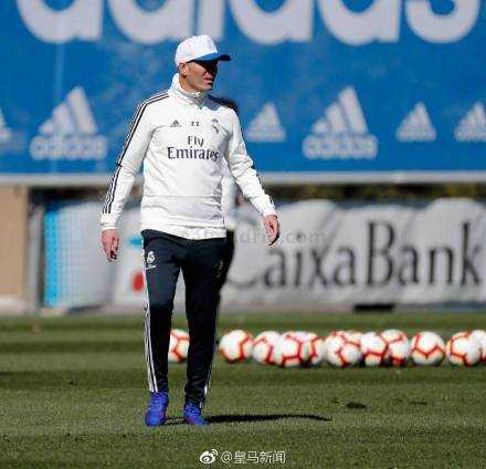 齐达内身穿白衣运动服，在训练场上露出标志性的温暖笑容，仿佛从未离开，眼神中透着坚定与从容。