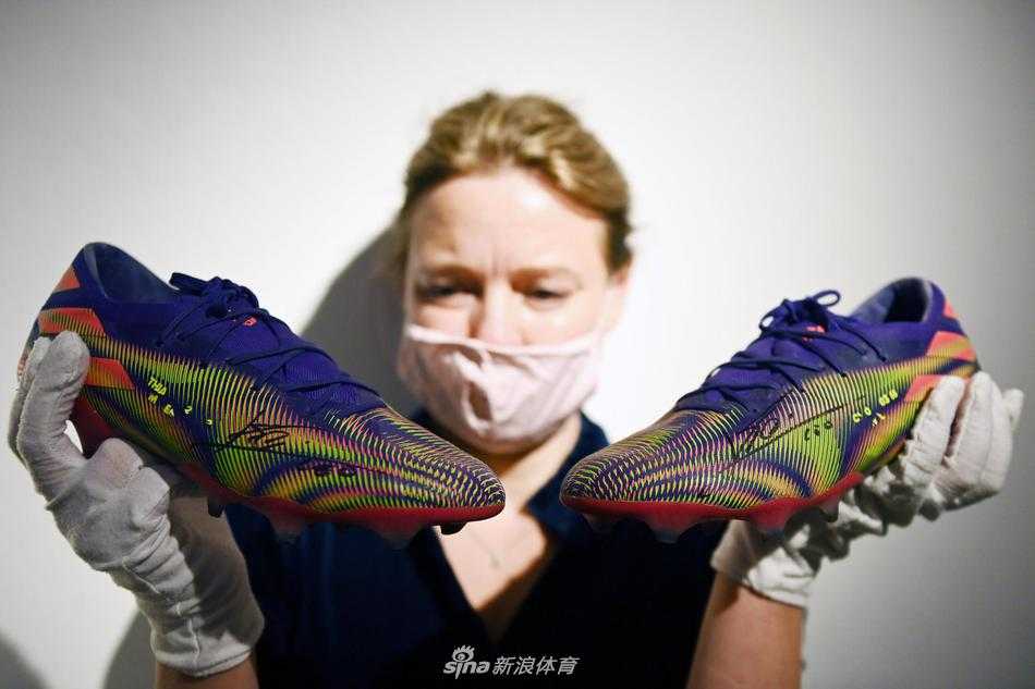 聚光灯下的英雄战靴，这双红黑配色的阿迪达斯球鞋静静陈列于展柜，鞋身上的每一道纹路都仿佛在诉说着它刚刚亲历的辉煌，它不仅是体育纪念品，更是一件即将传递爱心的艺术品。