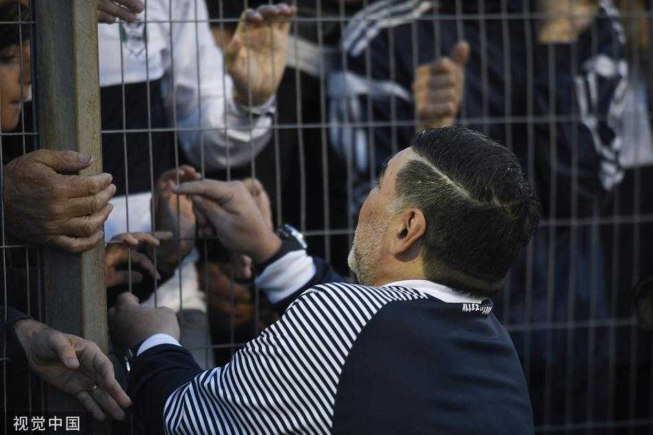 只见马拉多纳一脸严峻，右手紧握成拳高高举起，仿佛在向球员下达不容置疑的进攻指令，他的每一根神经都与球场的脉搏共同跳动。