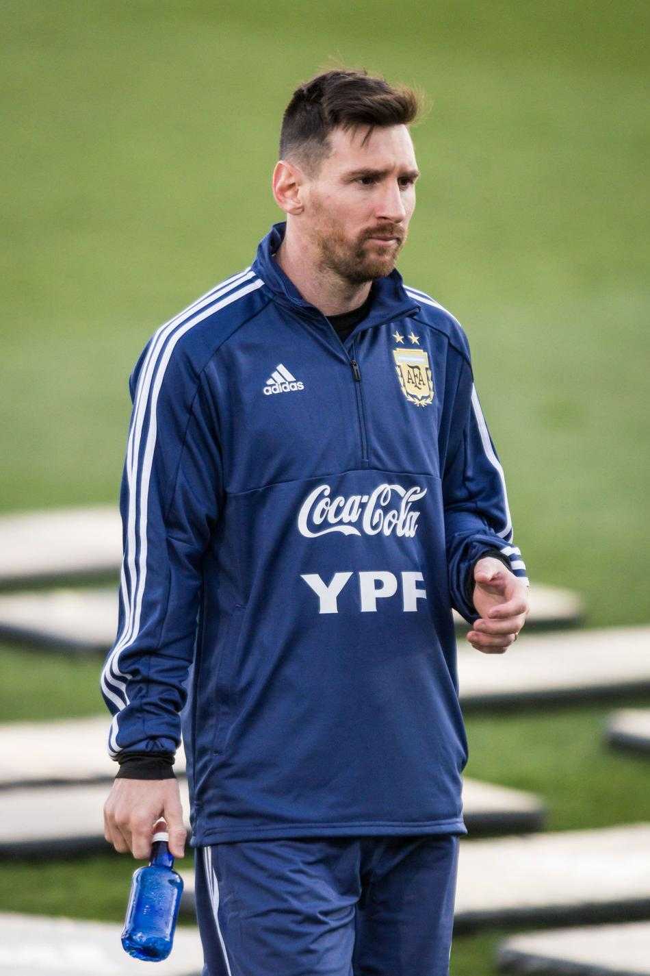 一个特写镜头捕捉到梅西坐在足球上的轻松瞬间，他双手自然放在膝盖上，嘴角微微上扬，眼神中透露出回归国家队的喜悦与平静。