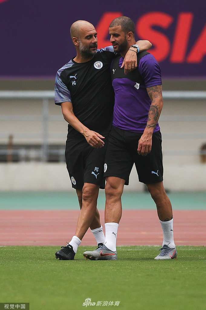 镜头特写瓜迪奥拉在南京训练时的一个瞬间，他表情专注，眼神坚定，汗水浸湿了衣衫，身后是模糊的球员身影和南京的夏日阳光。