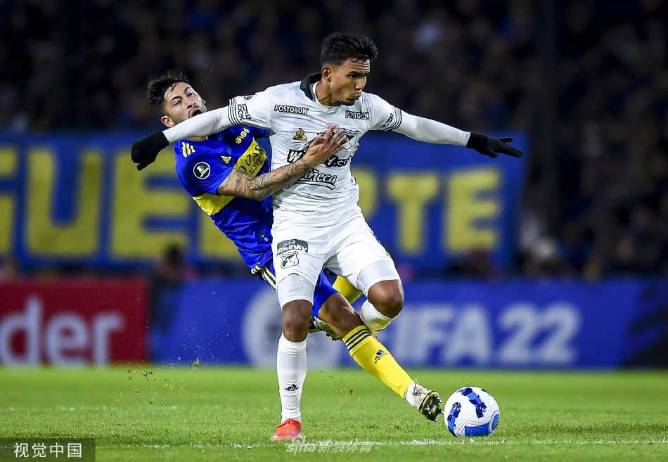 博卡青年队球员疯狂拥抱庆祝进球，他们身穿经典的蓝黄色间条衫，在绿色草皮的映衬下宛如一道冲破阴霾的闪电。