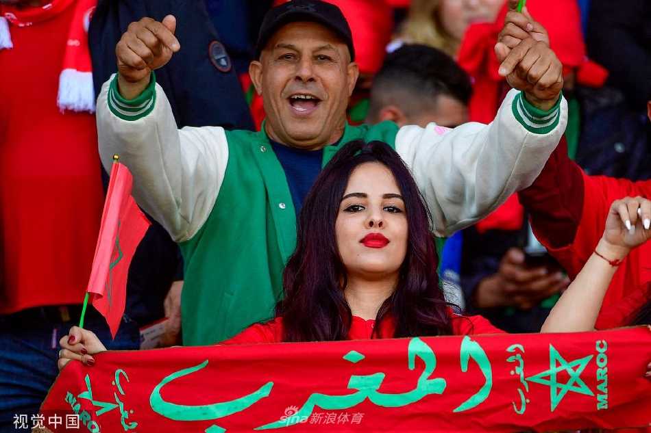 摩洛哥球员在万众欢呼中带球突破，红色球衣如火焰般在绿色草皮上划出一道闪电，防守球员紧追不舍，紧张气氛几乎溢出画面。