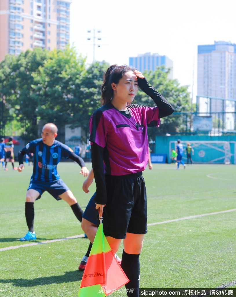 比赛间隙，这位女裁判脸庞被晒得微微泛红，但她神情专注，正通过与搭档简短的交流确认场上细节，一丝不苟的态度令人敬佩