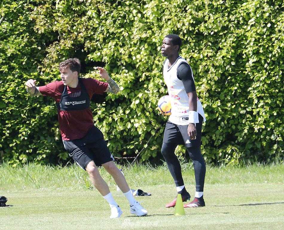 一名曼联球员在板球场边线附近进行高抬腿跑动热身，背景是空旷的看台和典型的英式板球俱乐部建筑，体育的跨界融合在此刻定格。