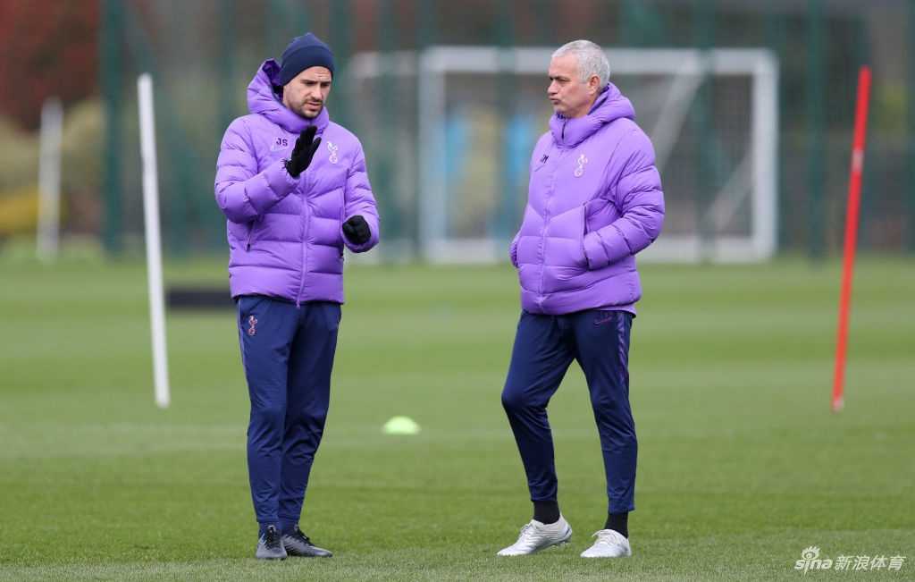 恩东贝莱在穆里尼奥的注视下进行带球训练，背景是伦敦公园空旷的绿地和远处的树木。