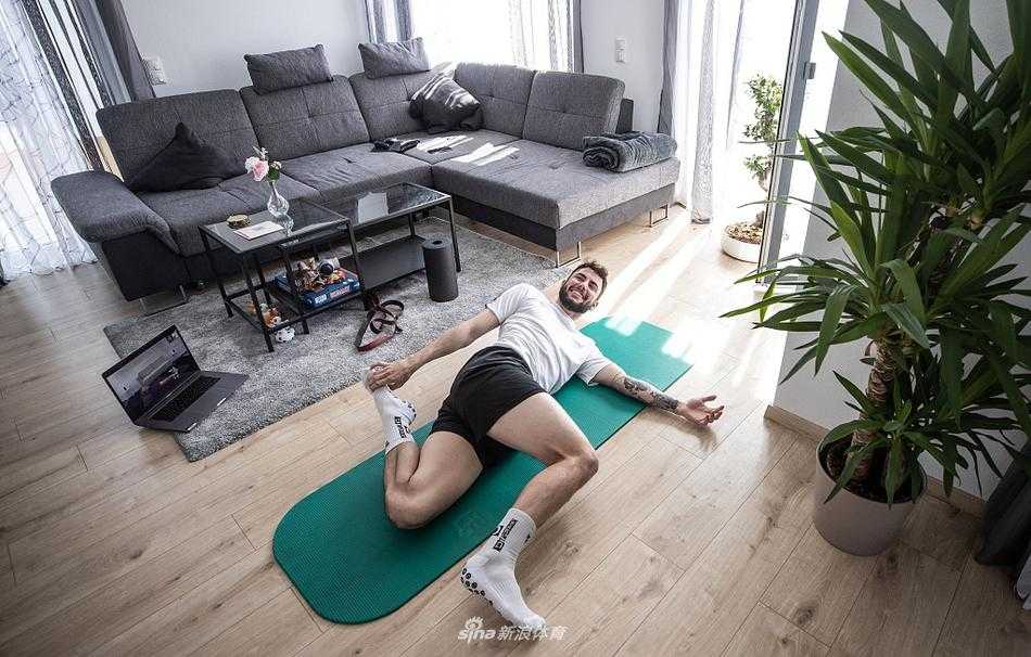 阳光透过窗户洒在里希特的背上，他正在进行瑜伽中的平衡体式，身体如一座稳固的雕塑，彰显着足球运动员柔韧与力量的完美结合。