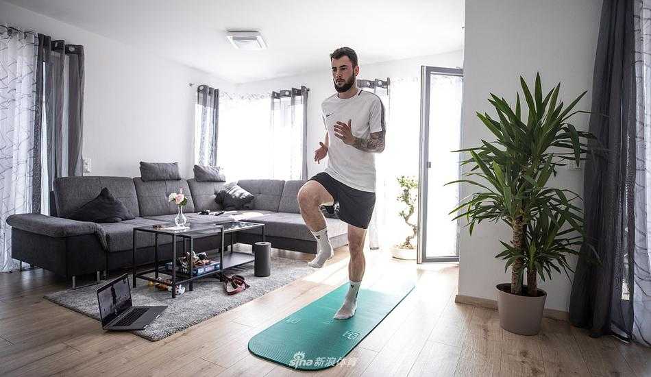 里希特在简易的居家健身区进行力量训练，眼神坚毅地望向镜头，身后的墙壁和简单的器械诉说着这段特殊时期里职业球员的坚守与执着。