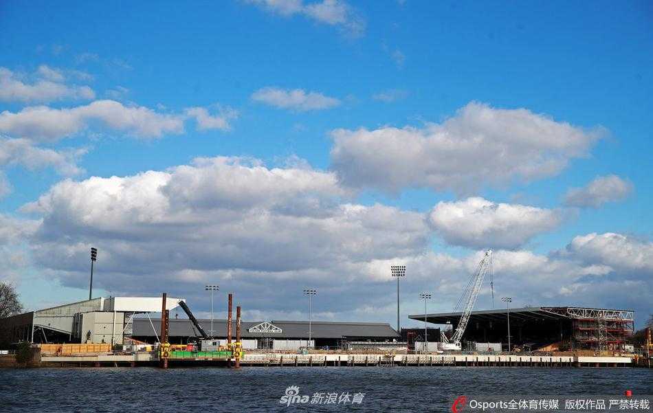 透过铁丝网的隔断望去，工地内部一片寂静，建材与施工机械被随意停放在泥泞中，远处红砖建筑的古老墙面与新搭建的钢架形成奇异的时空交错感。