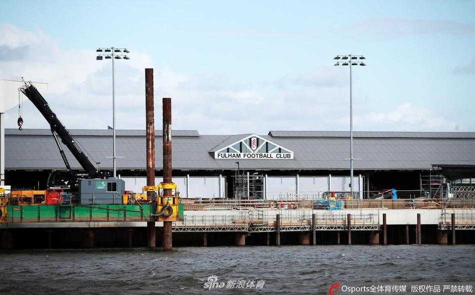 空旷的看台上，红色的座椅整齐排列却空无一人，对面河畔看台的改造工程静默停工，吊车长臂高悬，仿佛凝固在时光里，昔日喧嚣与今日寂静形成刺眼对比。