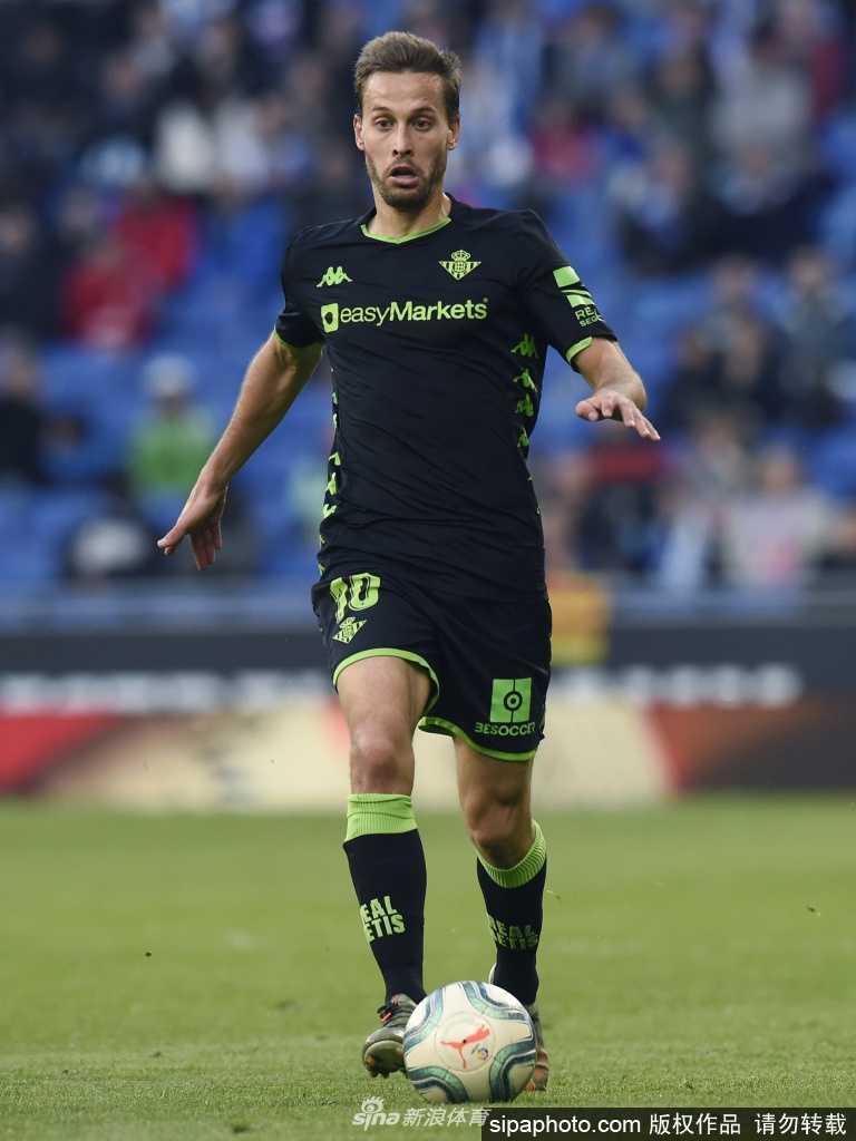 希望的传承：一位小球迷穿着贝蒂斯球衣，站在自家阳台上，手中举着一条写有‘一切都会好起来’的围巾。远处的街道空旷寂静，但他的眼神中充满了对足球回归和正常生活的渴望。