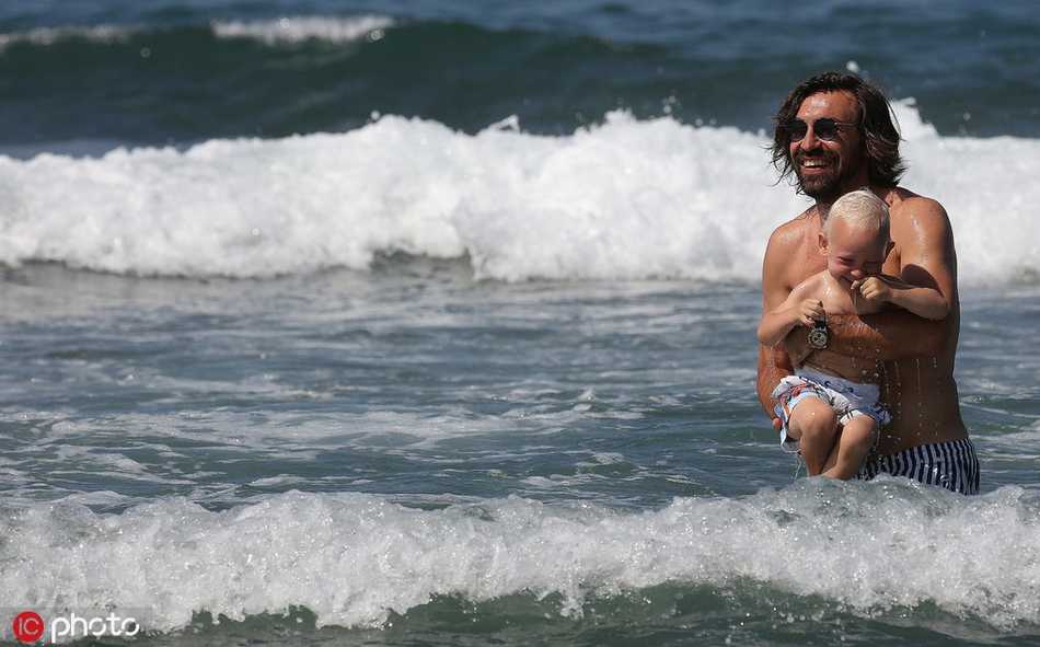 碧海蓝天之间，皮尔洛将幼子紧紧抱在怀中，父子二人共享清凉的海水，他脸上的笑容比阳光还要灿烂。