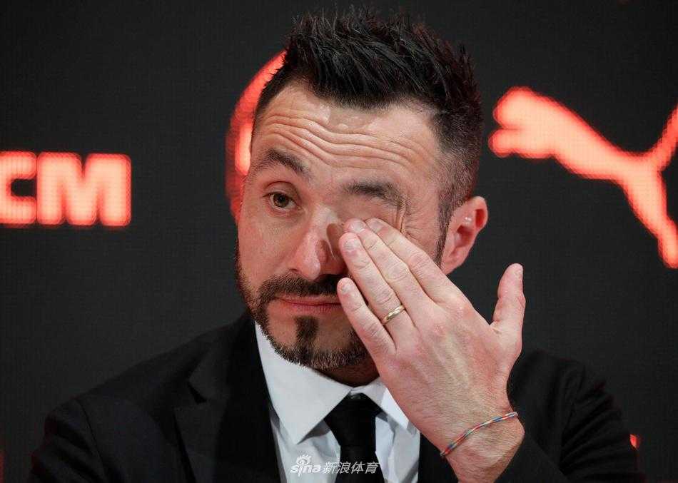 德泽尔比在新闻发布会上展露自信笑容，身后的矿工队徽熠熠生辉，预示着一个全新时代的开启。