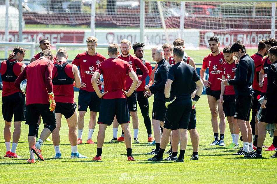 在晴空下，纽伦堡球员们围成一圈，听着教练的战术部署，眼神中透露出对胜利的渴望和保级的决心。