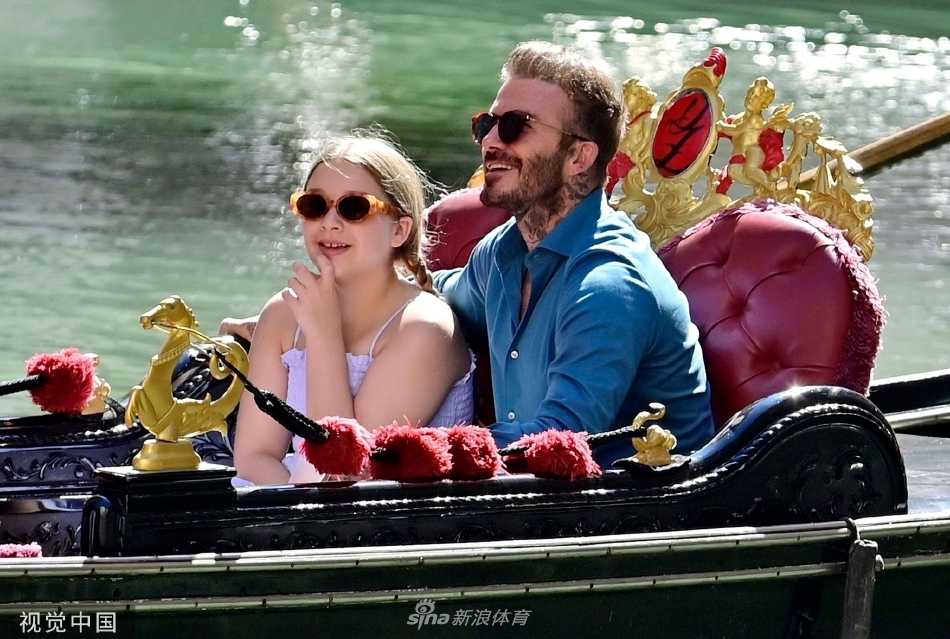 小七独立坐在船边，手扶船舷回眸浅笑，背景是威尼斯的古典建筑与蓝天白云，少女的清新与水城的浪漫相得益彰。