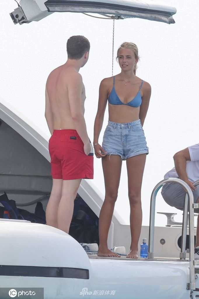 米歇尔·格尔齐格身着白色泳装，倚靠在游艇栏杆上回眸一笑，展现出超模的迷人风采。