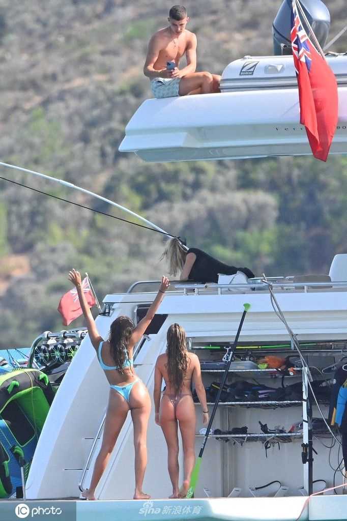 索菲亚身着黑色泳装，外搭轻纱罩衫，倚靠在游艇舒适的沙发座椅上，展现出优雅与性感并存的度假风情。