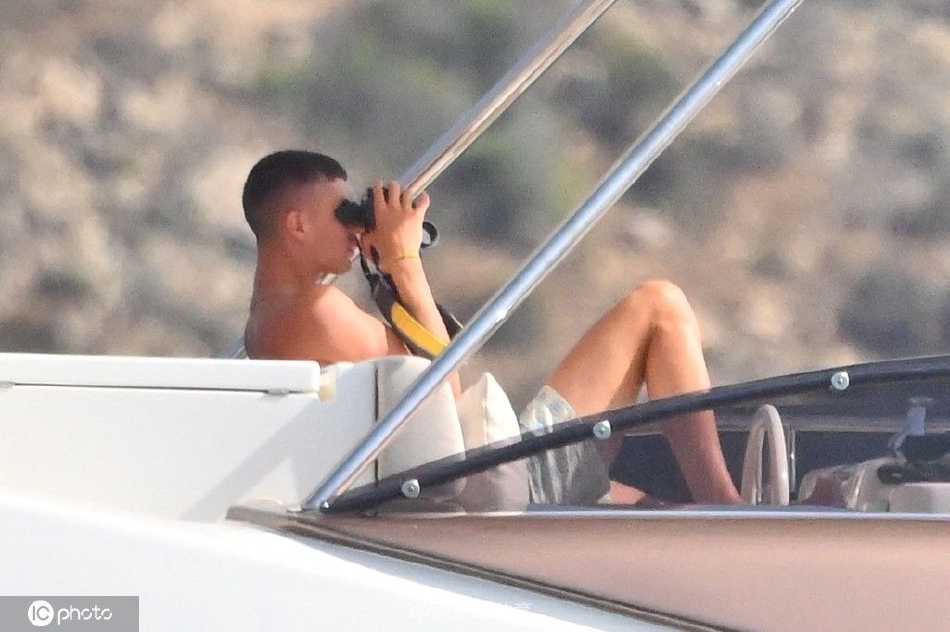 两人面对面坐在游艇餐桌旁，似乎在分享有趣的见闻，哈弗茨身体前倾，神情专注，索菲亚则笑得眉眼弯弯。