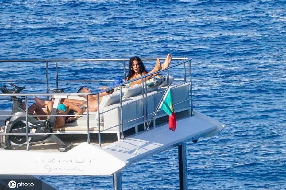 C罗戴着墨镜进行水上活动，手臂肌肉线条与背景中的海岛风光相映衬，活力四射