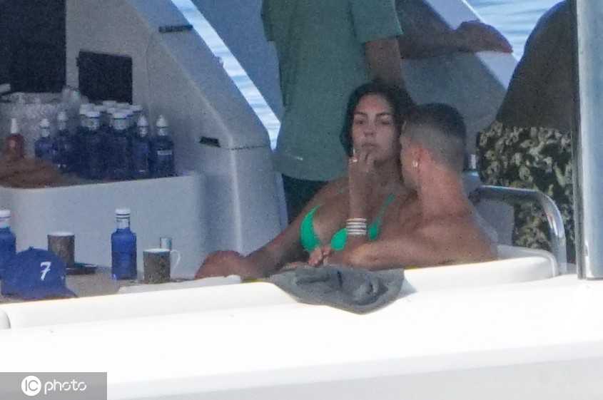 乔治娜身穿黑色比基尼展现自信身材，C罗紧挨身旁，两人在阳光下轻声交谈，氛围轻松惬意