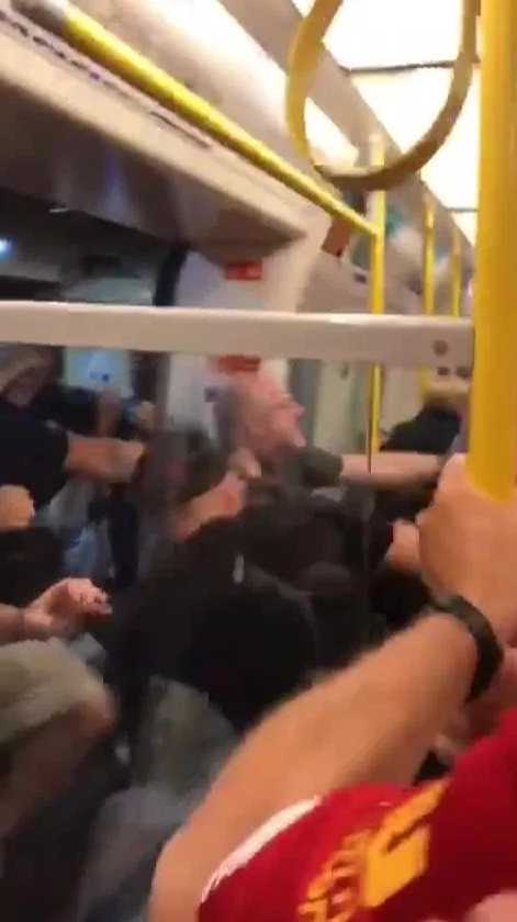 冲突暂歇的地铁车厢内一片狼藉，地上散落着疑似啤酒瓶的物品，一名男子神色凝重地站着，似乎在为刚才的失控场面感到后悔。