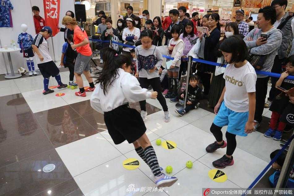 福冈永旺商场内，宽阔的中央区域被临时改造成了绿茵场地。一群穿着全套专业球衣球鞋的孩子们正在教练的指导下进行趣味热身，他们专注的神情和稚嫩却认真的动作，瞬间点燃了整个商场的活力。